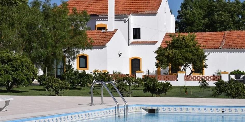 Det hvide hovedhus med gule kanter ved poolen